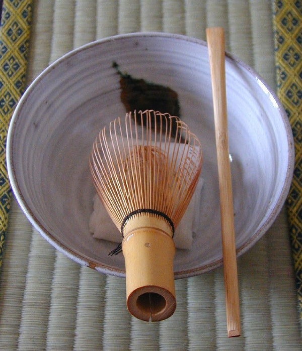 Japanese tea bowl with bamboo whisk, tea scoop and folded white chakin cloth inside