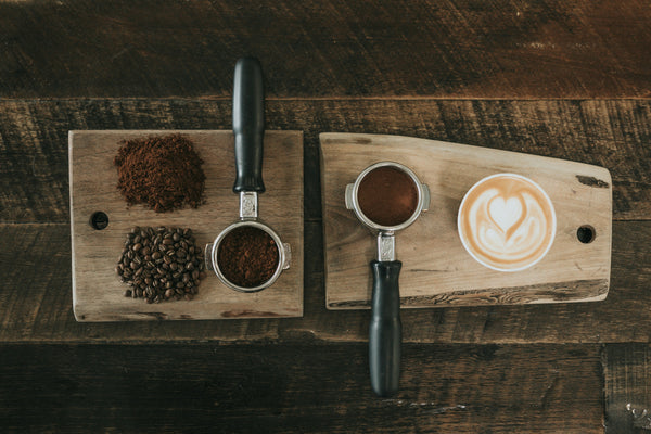 Whole coffee beans beside ground coffee on a wooden board