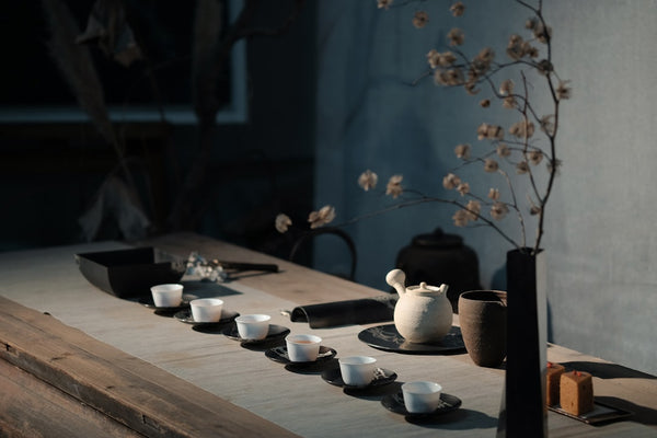 Tea set with small white cups and a teapot on a wooden table
