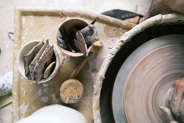 Hands shaping clay on a pottery wheel, illustrating craft guided by a specific design