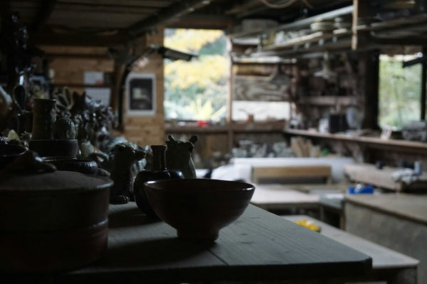 Black ceramic bowl in a pottery workshop used as a clay-form reference; not a verified Benibachi furo