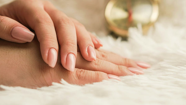 A hand with natural nails resting on white fabric