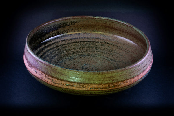 Handmade dark ceramic bowl on a plain surface