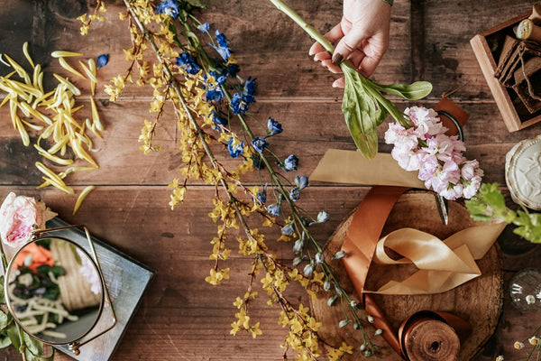 Person holding blue and white flowers while preparing a flower arrangement