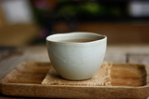 Handleless white ceramic tea cup on a wooden table