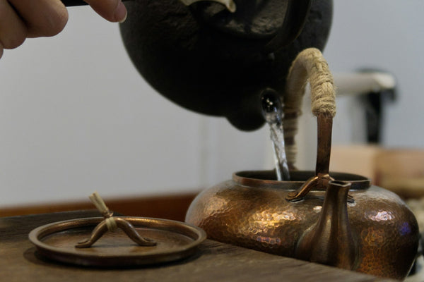 Fresh water being poured into a dark Japanese-style teapot