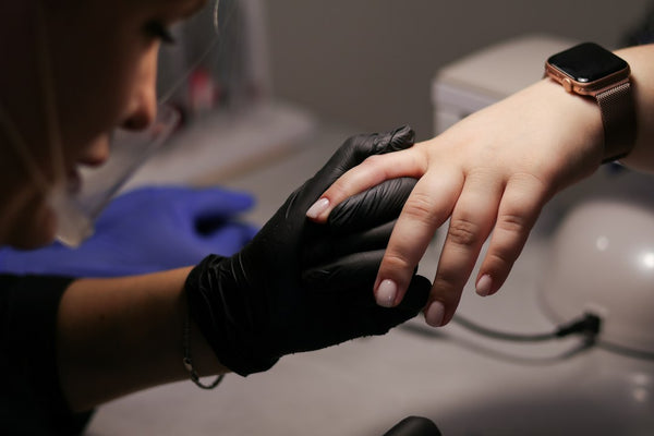 Professional manicure being performed with gloved hands