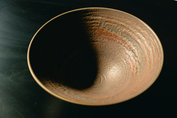 Handmade brown ceramic bowl illustrating the earthy tactile qualities associated with Japanese tea pottery