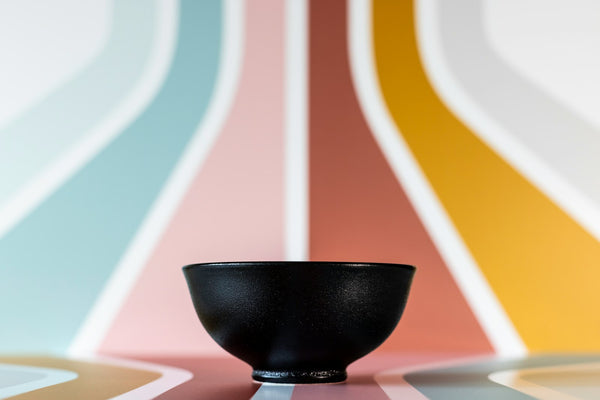 Dark ceramic bowl used only as a material-and-form reference for the rounded body of a Mayu furo; not a verified tea brazier