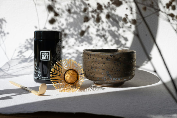 Bamboo chasen beside a matcha bowl and tea tools