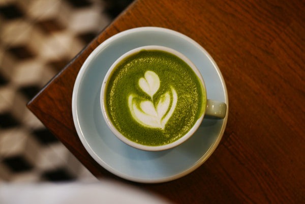 Green matcha latte with latte art in a ceramic cup