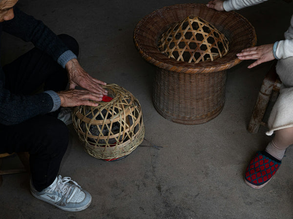 Hands working with woven bamboo baskets in a craft setting