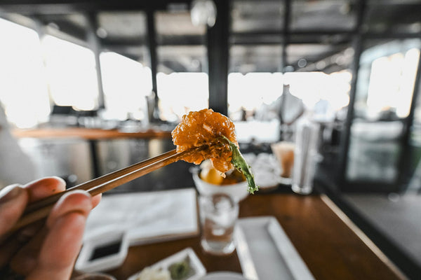 Hand using chopsticks to lift food at a Japanese restaurant