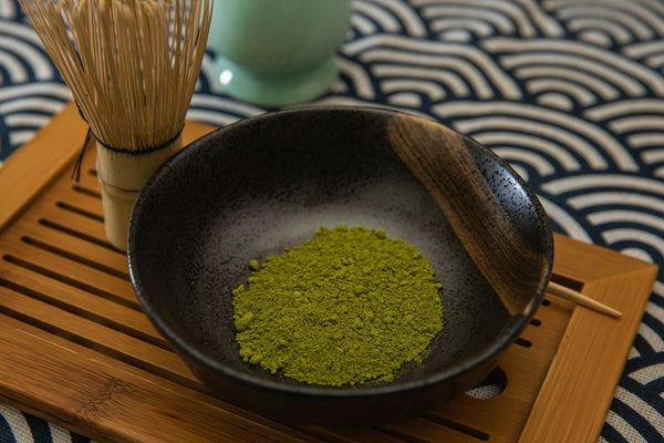 Fine matcha powder in a bowl beside a bamboo chasen