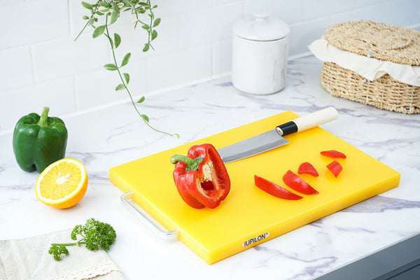 Japanese kitchen knife and sliced red pepper on a yellow plastic cutting board