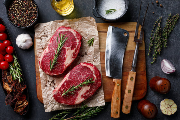 Raw meat and a kitchen knife on a cutting board