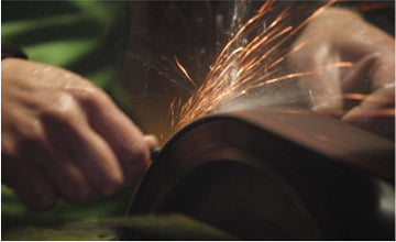 Kitchen knife blade being ground on a belt with sparks