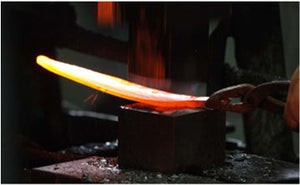 Hot forged kitchen knife blade resting on an anvil