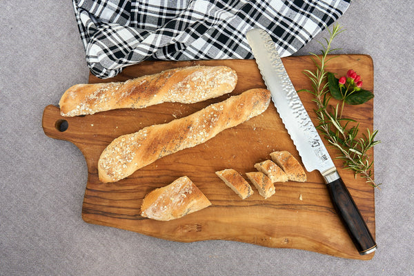 Bread and a kitchen knife on a wooden cutting board