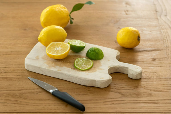 Sliced lemon and kitchen knife on a wooden cutting board