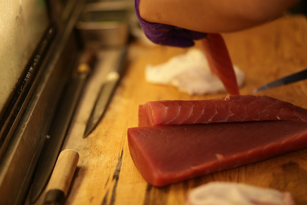 Fresh tuna being prepared with a long kitchen slicing knife