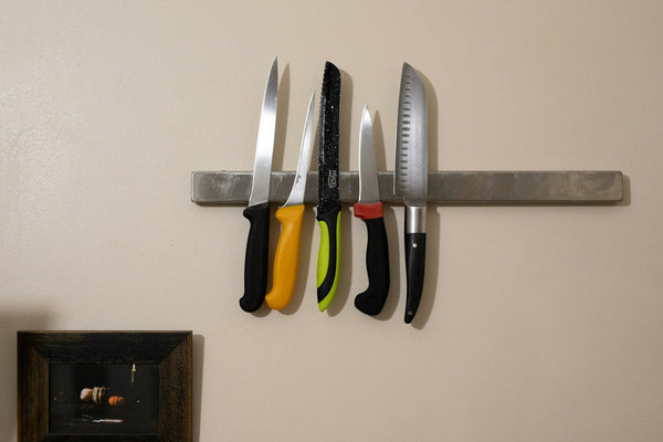 Several kitchen knives arranged together on a wall-mounted rack
