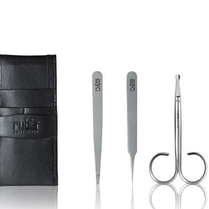 A set of three silver metal beauty tools, including tweezers, a spatula, and a loop tool, displayed next to a black leather card holder case on a reflective white background. The brand name 'rubie' is embossed on the case and engraved on the tools.